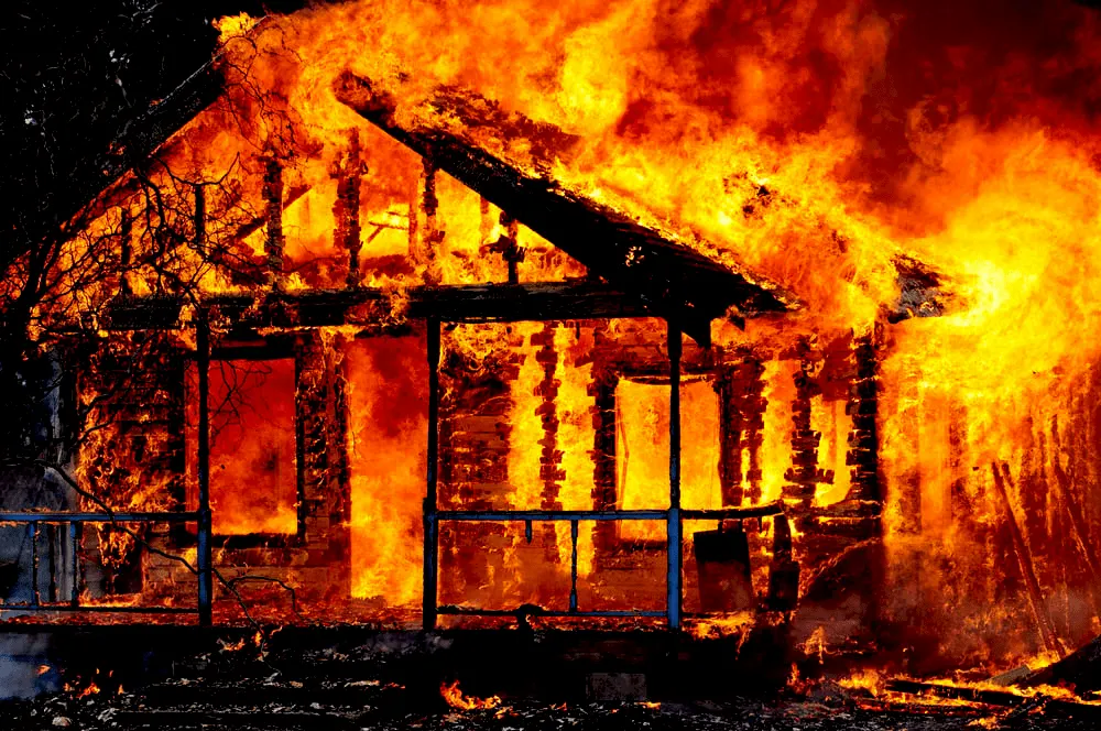 Ein brennendes Holzhaus in der Nacht, welches schon fast vollständig ausgebrannt ist