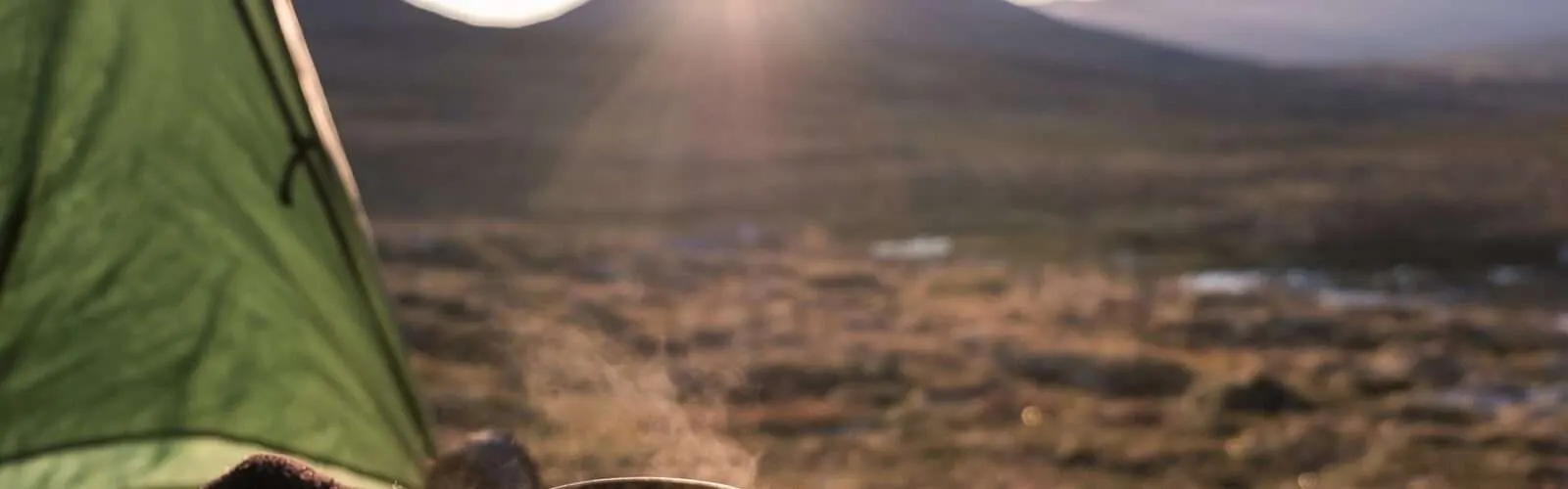 Ein Survival Lager in er Wildnis mit Blick in die weite Landschaft bei Sonnenaufgang