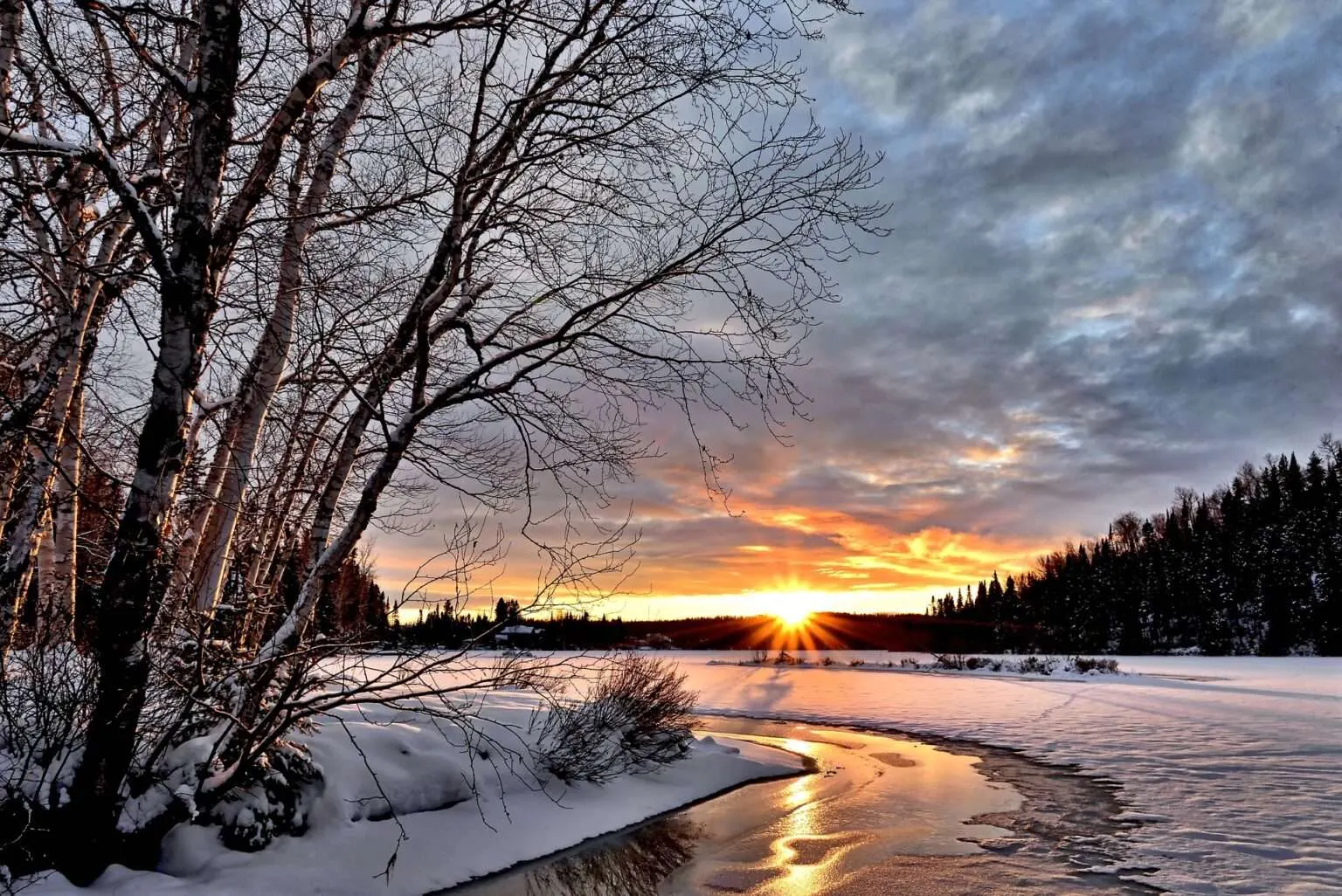 Ein eisiger Flusslauf in einer Winterlandschaft bei Sonnenuntergang